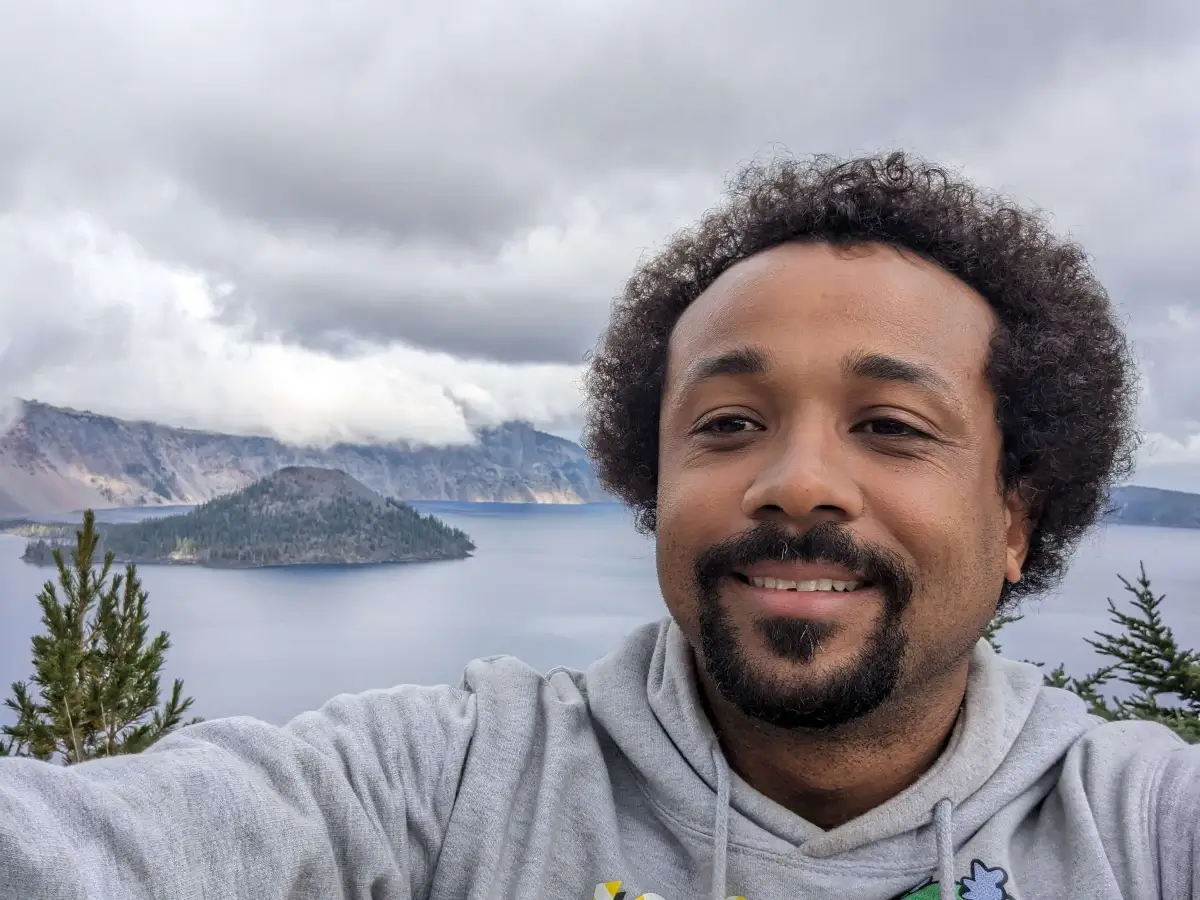 Crvne taking a selfie on the rim of Crater Lake with Wizard Island in the background.