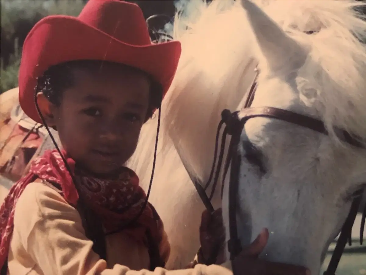 Crvne posing in cowboy regalia with a horse.
